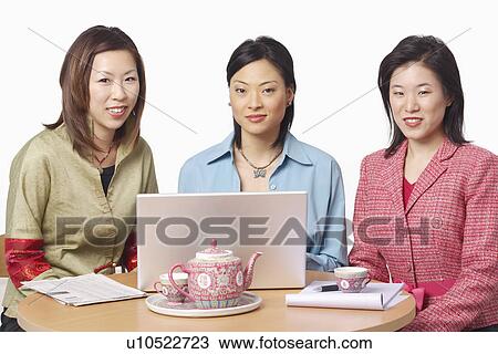 Portrait of three businesswomen in front of a laptop View Large Photo Image Stock Image - Portrait of three businesswomen in front of a laptop. Fotosearch