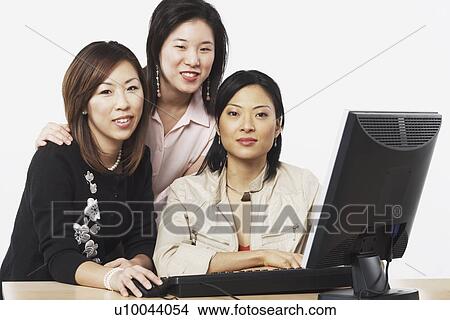 Portrait of three businesswomen smiling in front of a computer View Large Photo Image Picture - Portrait of three businesswomen smiling in front of a computer. Fotosearch
