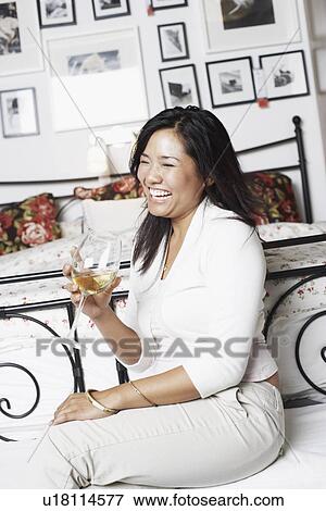 Stock Photo - Side profile of a young woman holding a glass of wine smiling. Fotosearch