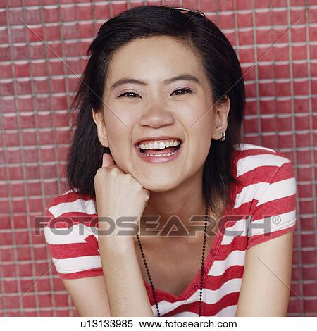 Stock Photography - Portrait of a young woman smiling with her hand on her chin. Fotosearch