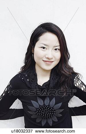 Portrait of a young woman standing with her hands behind her back smiling View Large Photo Image Stock Photo - Portrait of a young woman standing with her hands behind her back smiling. Fotosearch
