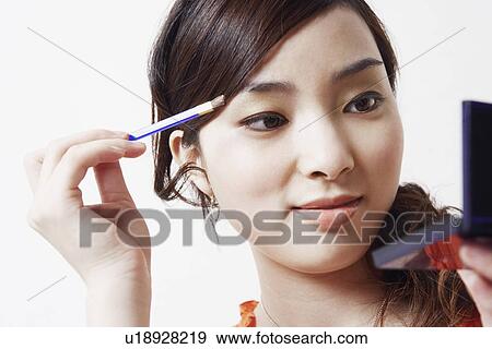 Close-up of a young woman holding a make-up brush and a hand mirror View Large Photo Image Stock Photo - Close-up of a young woman holding a make-up brush and a hand mirror. Fotosearch