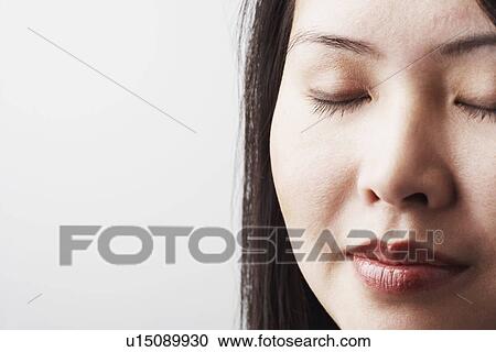 Stock Image - Close-up of a young woman meditating with her eyes closed. Fotosearch