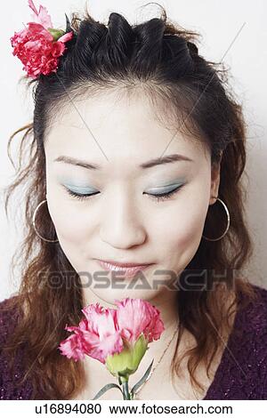 Close-up of a young woman smelling a flower View Large Photo Image Stock Image - Close-up of a young woman smelling a flower. Fotosearch