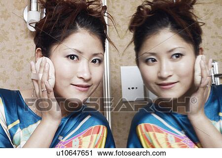 Stock Image - Portrait of a teenage girl applying face powder. Fotosearch