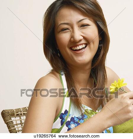 Picture - Portrait of a young woman holding a flower and smiling. Fotosearch
