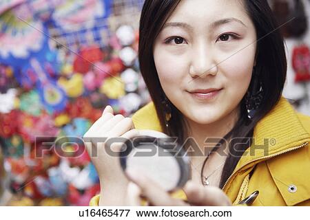 Portrait of a young woman holding a vanity mirror View Large Photo Image Stock Photo - Portrait of a young woman holding a vanity mirror. Fotosearch