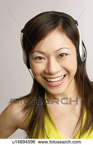 Portrait of a young woman listening to music and smiling View Large Photo Image Stock Photograph - Portrait of a young woman listening to music and smiling. Fotosearch