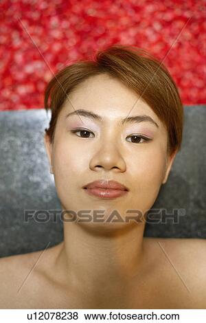 Stock Photo - Portrait of a young woman lying on floor near a hot tub filled with rose petals. Fotosearch