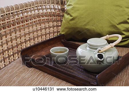 Stock Image - Close-up of a teapot and a tea cup with a tray in an armchair. Fotosearch