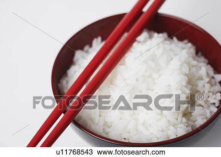 Stock Image - High angle view of a pair of chopsticks on a bowl of rice. Fotosearch