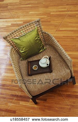 Stock Photo - High angle view of a teapot and a tea cup with a tray in an armchair. Fotosearch