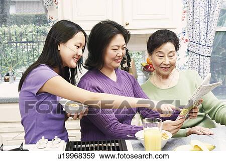 Stock Photo - Mother with her daughter and a senior woman reading a newspaper. Fotosearch