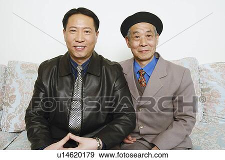 Stock Photo - Portrait of a father sitting on a couch with his son smiling. Fotosearch