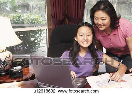 Stock Image - Portrait of a girl and her mother in front of a laptop. Fotosearch