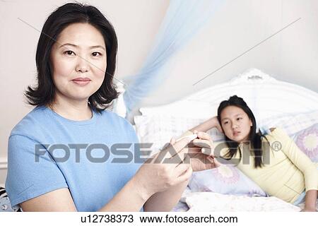Stock Image - Portrait of a mother checking her daughter's temperature. Fotosearch