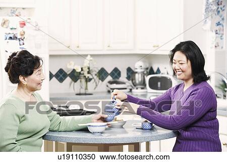 Side profile of a girl pouring tea for her mother View Large Photo Image Stock Image - Side profile of a girl pouring tea for her mother. Fotosearch