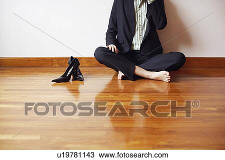 Stock Image - Businesswoman sitting cross-legged on the hardwood floor. Fotosearch