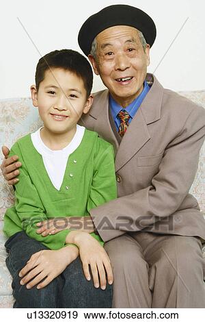 Stock Photo - Portrait of a boy sitting on a couch with his grandfather smiling. Fotosearch
