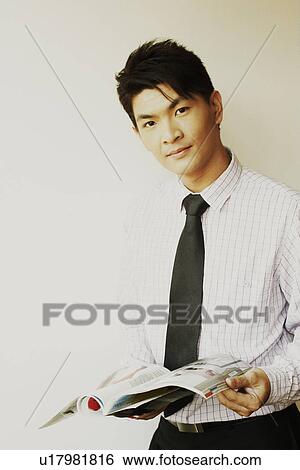 Stock Photograph - Portrait of a businessman holding a magazine. Fotosearch
