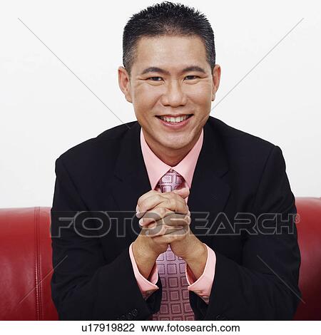 Stock Image - Portrait of a businessman sitting on a couch and smiling. Fotosearch