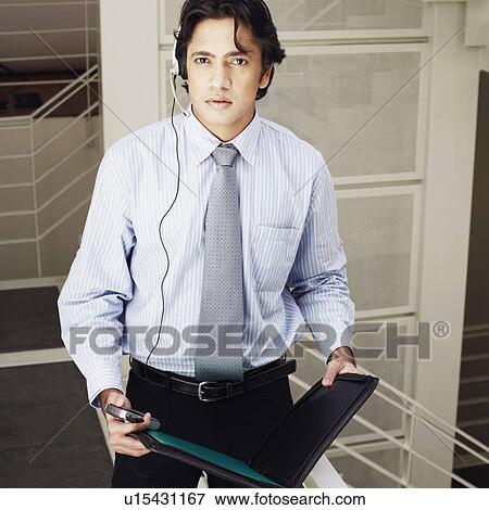 Stock Photo - Portrait of a male customer service representative holding a file and a mobile phone. Fotosearch