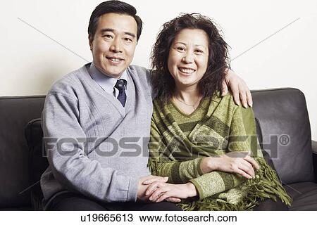 Portrait of a mature couple sitting together on a couch smiling View Large Photo Image Stock Image - Portrait of a mature couple sitting together on a couch smiling. Fotosearch