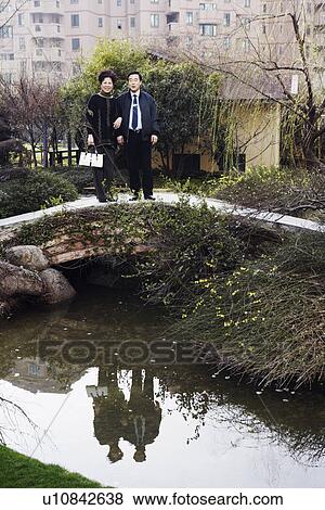Portrait of a mature couple standing on a footbridge smiling View Large Photo Image Stock Photo - Portrait of a mature couple standing on a footbridge smiling. Fotosearch
