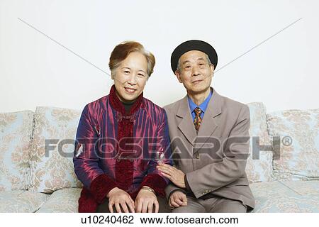 Stock Image - Portrait of a senior man sitting on a couch with a mature woman. Fotosearch
