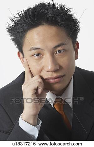 Stock Photograph - Portrait of a young man with his hand on his face. Fotosearch