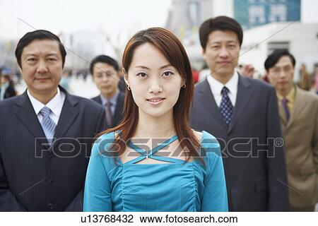 Stock Image - Portrait of a young woman standing with four businessmen. Fotosearch