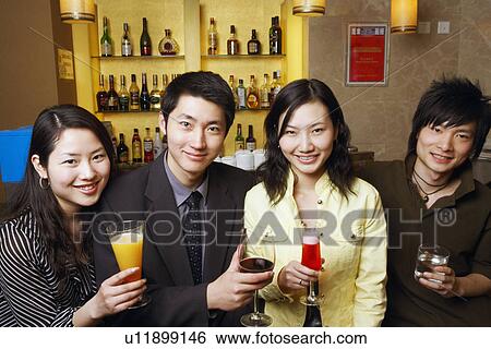 Stock Photograph - Portrait of four friends holding drinks. Fotosearch