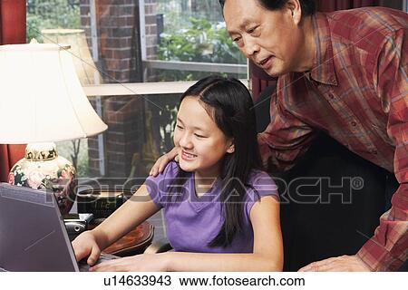 Close-up of a girl using a laptop with her father behind her View Large Photo Image Stock Image - Close-up of a girl using a laptop with her father behind her. Fotosearch
