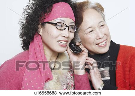 Close-up of a mature woman with her friends and using a mobile phone View Large Photo Image Stock Photo - Close-up of a mature woman with her friends and using a mobile phone. Fotosearch