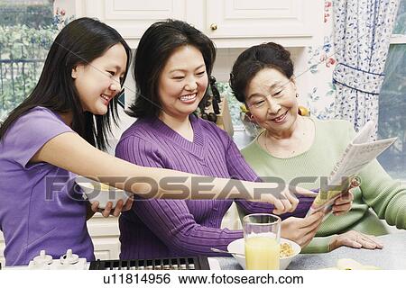 Stock Photograph - Close-up of a mother with her daughter and a senior woman reading a newspaper. Fotosearch