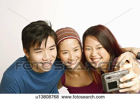 Stock Photo - Close-up of a young woman and a young couple taking a picture. Fotosearch