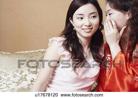 Close-up of a young woman whispering secrets into her friend's ear View Large Photo Image Stock Image - Close-up of a young woman whispering secrets into her friend's ear. Fotosearch