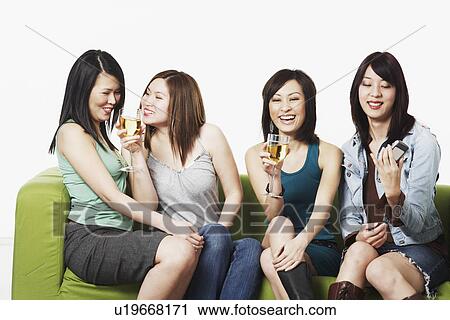 Stock Image - Close-up of four young women sitting on a couch smiling. Fotosearch