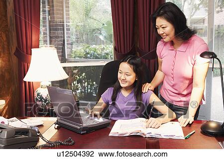 Stock Image - High angle view of a girl and her mother in front of a laptop. Fotosearch