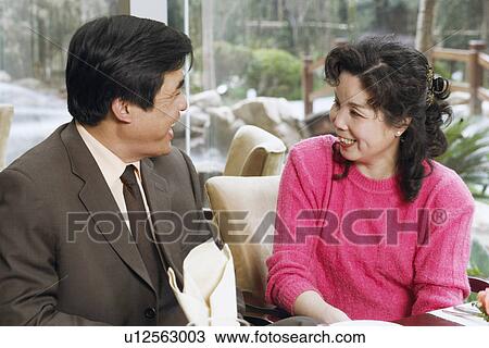 Stock Image - Mature couple sitting in a restaurant looking at each other. Fotosearch