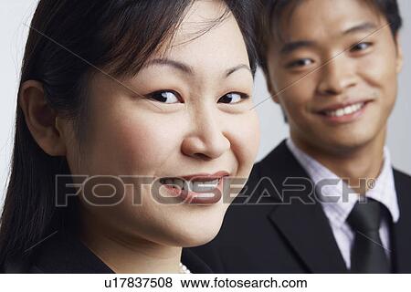 Portrait of a businesswoman smiling with a businessman beside her View Large Photo Image Stock Photo - Portrait of a businesswoman smiling with a businessman beside her. Fotosearch