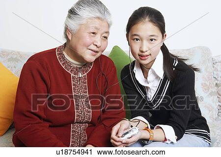 Portrait of a young woman sharing headphones with her grandmother View Large Photo Image Stock Image - Portrait of a young woman sharing headphones with her grandmother. Fotosearch