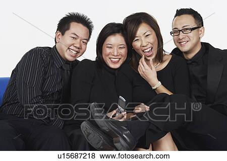 Stock Photo - Portrait of two young men and two young women sitting on a couch. Fotosearch