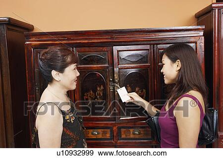 Side profile of a mature woman with her daughter smiling in font of an almirah View Large Photo Image Stock Photo - Side profile of a mature woman with her daughter smiling in font of an almirah. Fotosearch