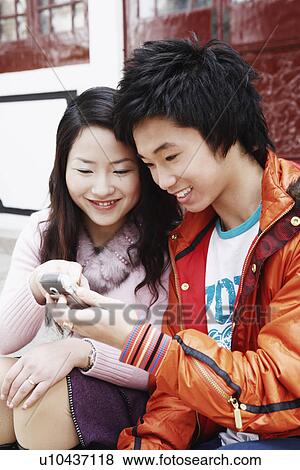Stock Photo - Teenage boy sitting with a young woman holding a mobile phone. Fotosearch