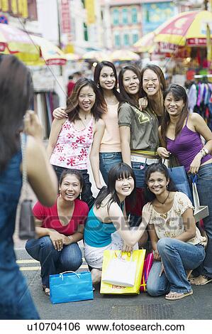 Stock Photograph - Young woman taking a photograph of her friends. Fotosearch