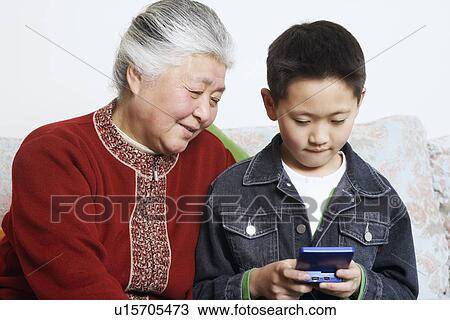 Stock Image - Close-up of a boy and his grandmother playing a video game. Fotosearch
