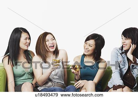 Stock Photo - Close-up of four young women sitting on a couch smiling. Fotosearch