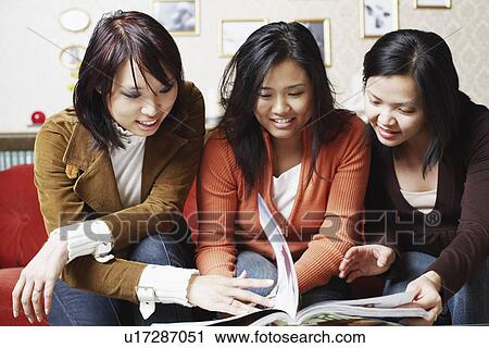 Close-up of three friends looking at a magazine View Large Photo Image Stock Image - Close-up of three friends looking at a magazine. Fotosearch