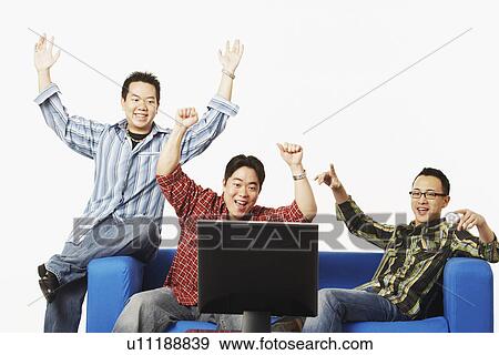 Close-up of three young men cheering in front of a flat screen monitor View Large Photo Image Stock Photo - Close-up of three young men cheering in front of a flat screen monitor. Fotosearch